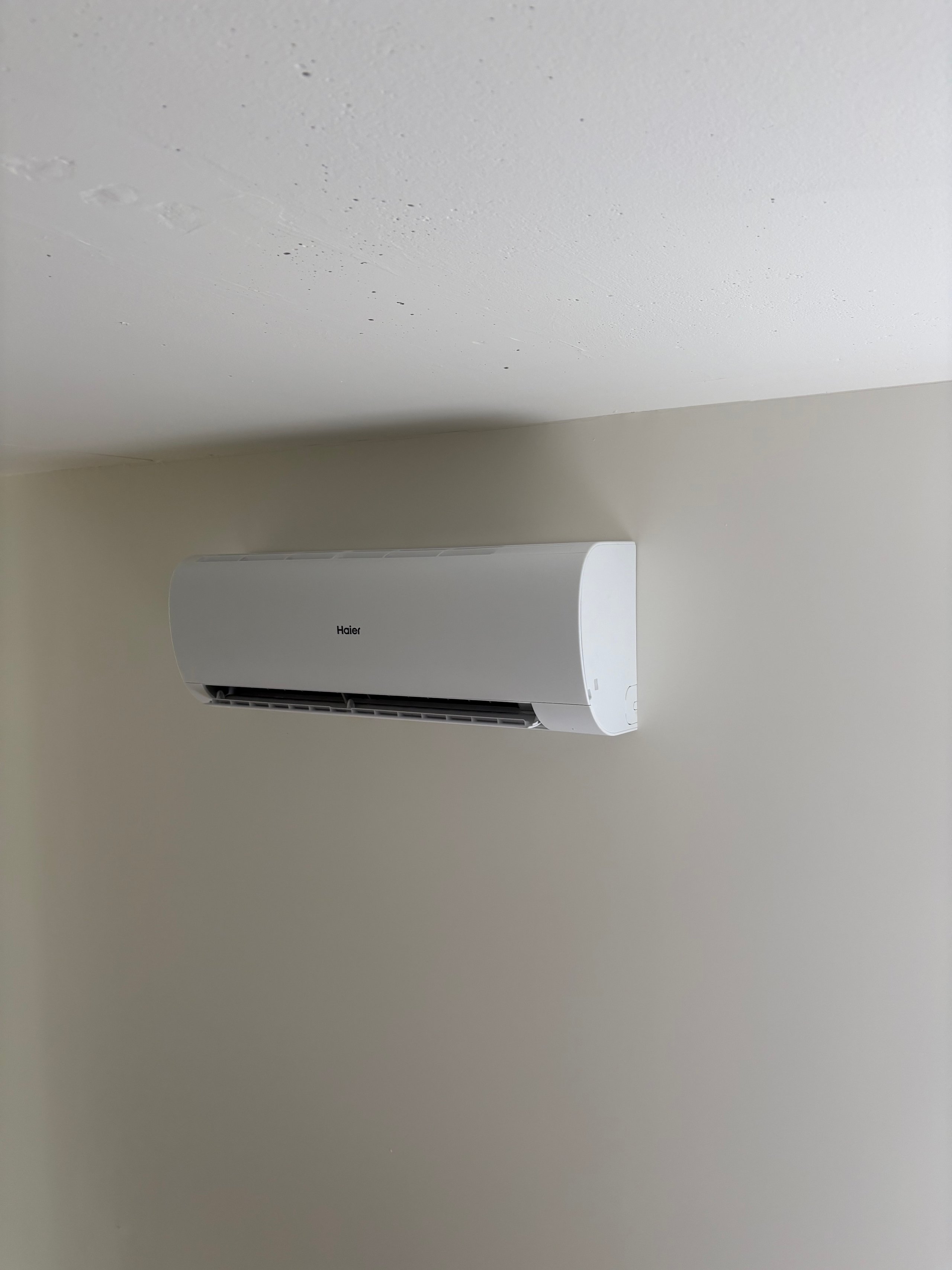 White Haier air conditioning unit mounted on a beige wall
