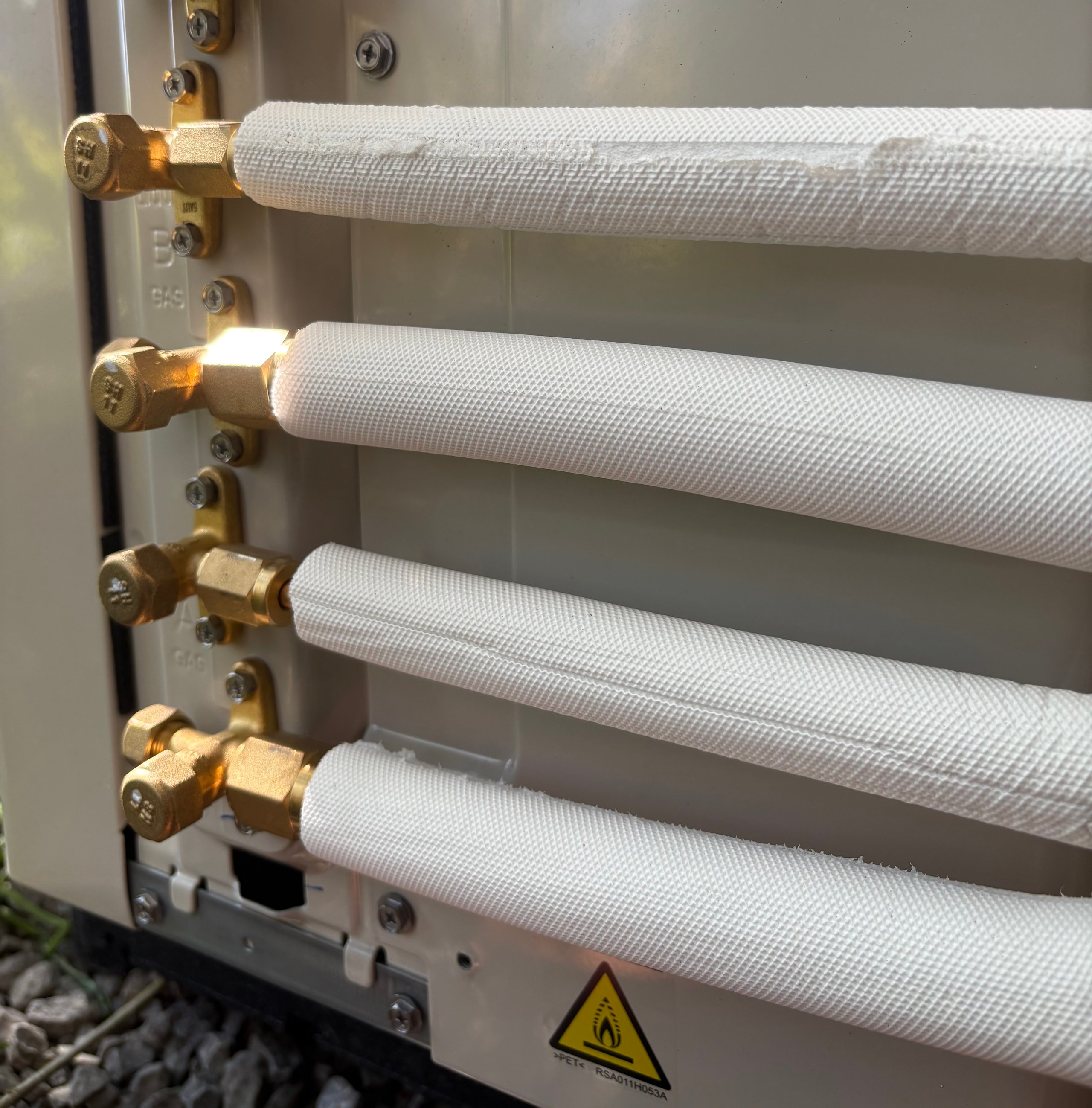 Four white coiled refrigerant tubes with brass connectors