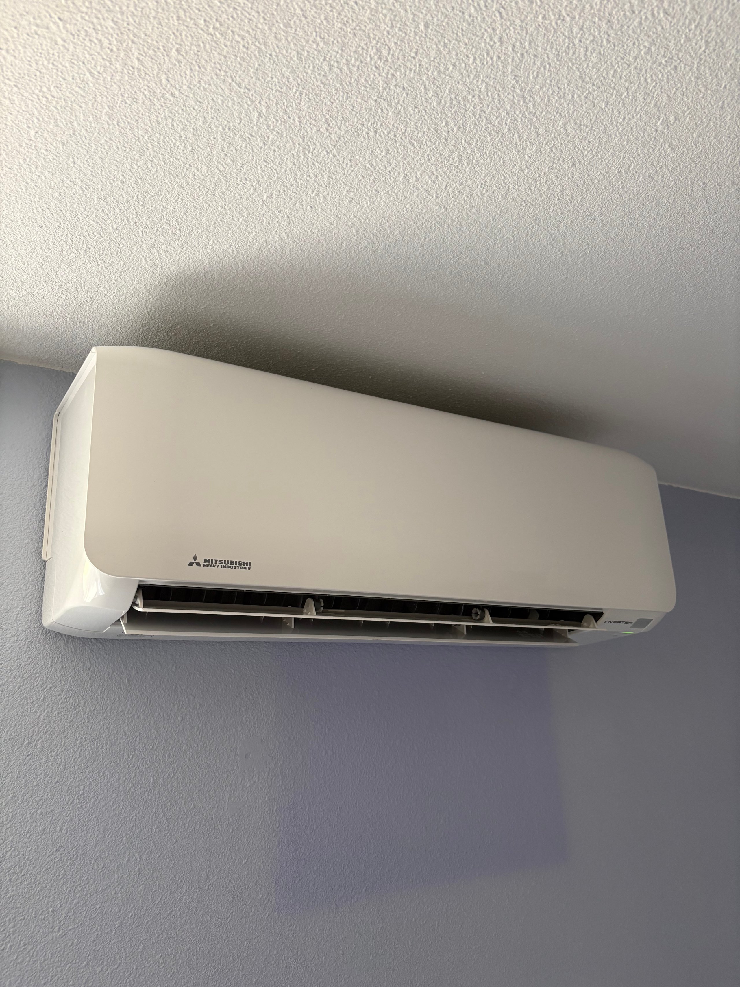 White Mitsubishi air conditioning unit mounted on a beige wall