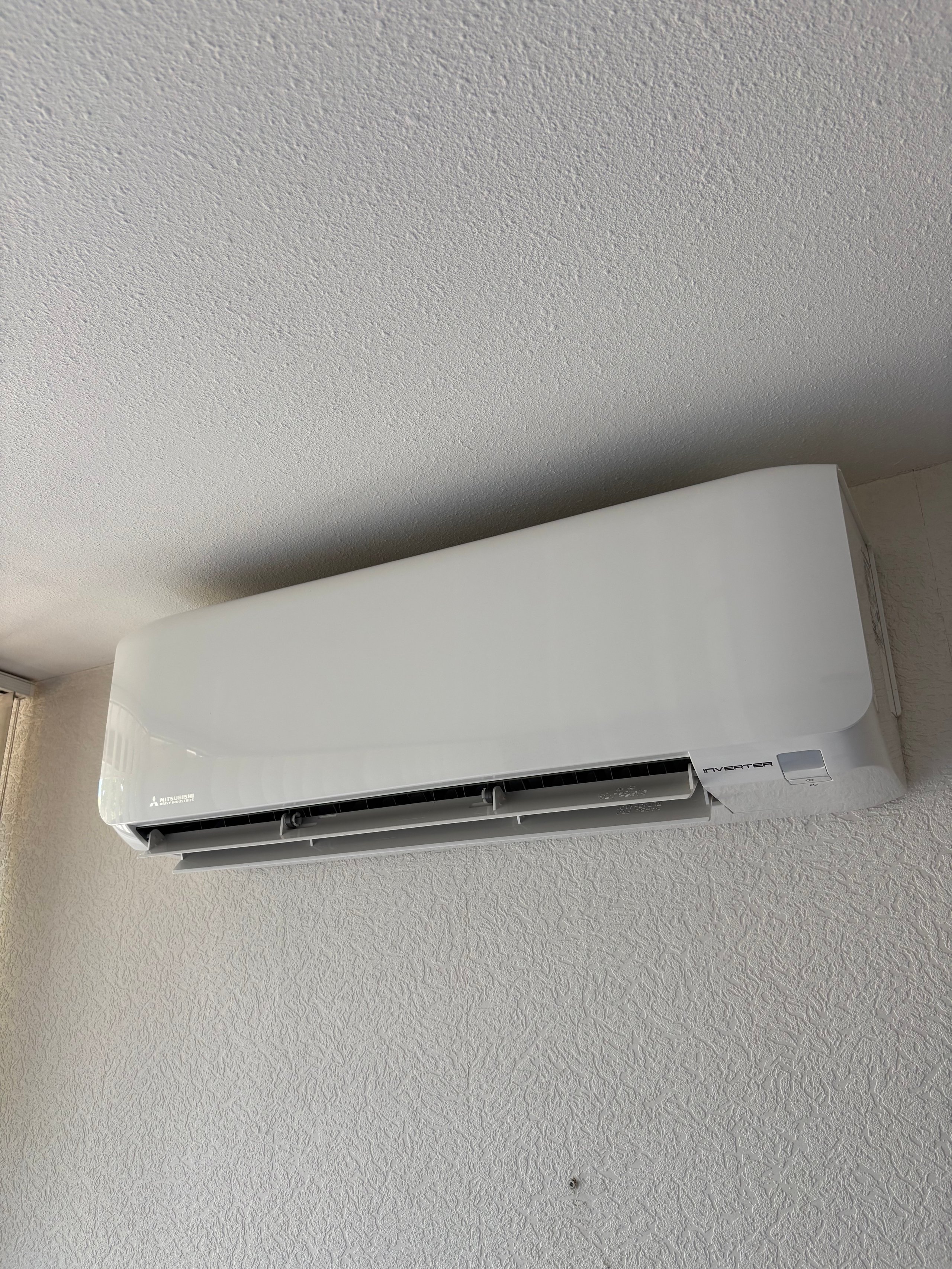 White ductless air conditioning unit mounted on a textured gray wall