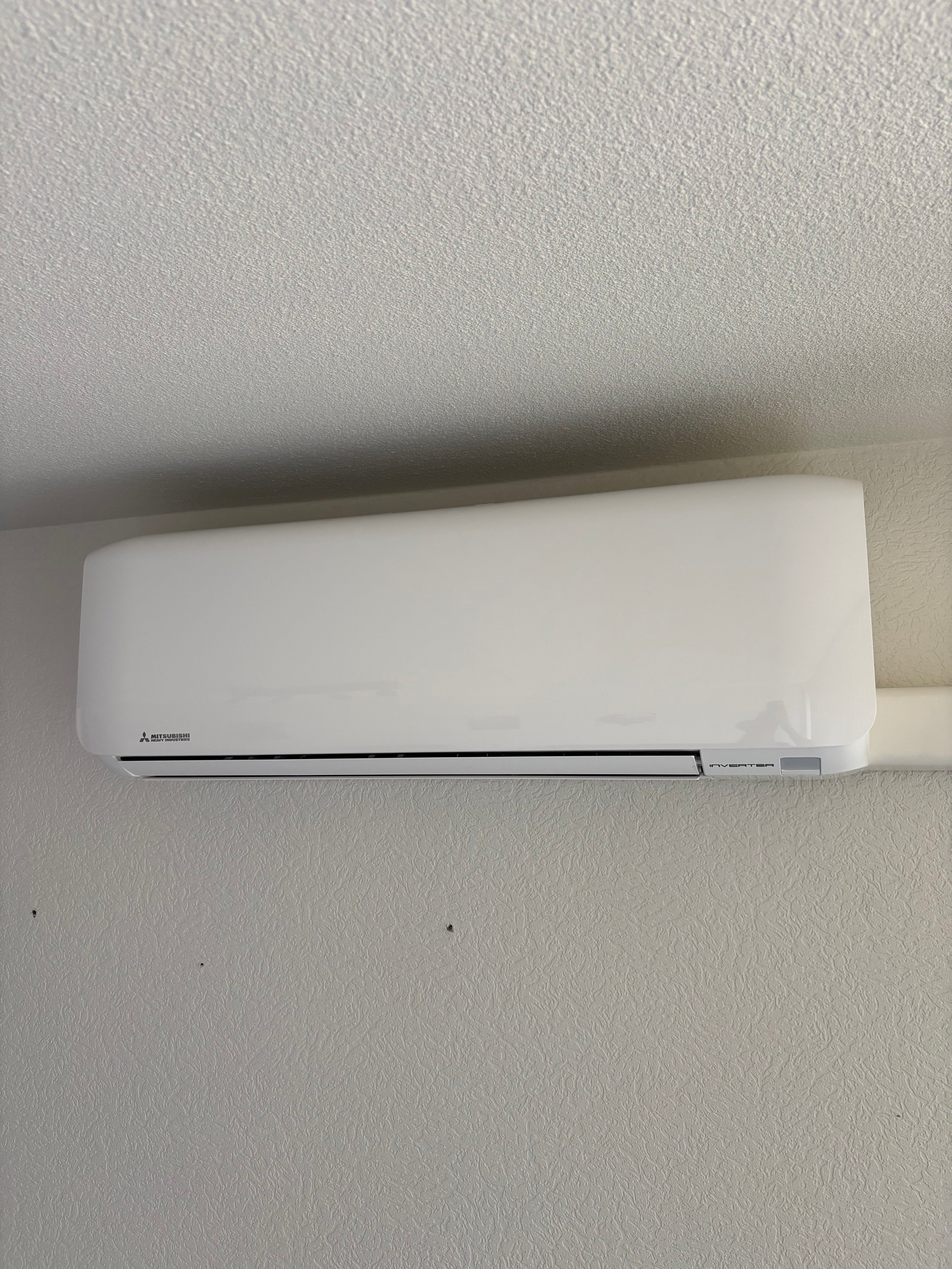 White Mitsubishi wall-mounted air conditioning unit installed on a light ceiling