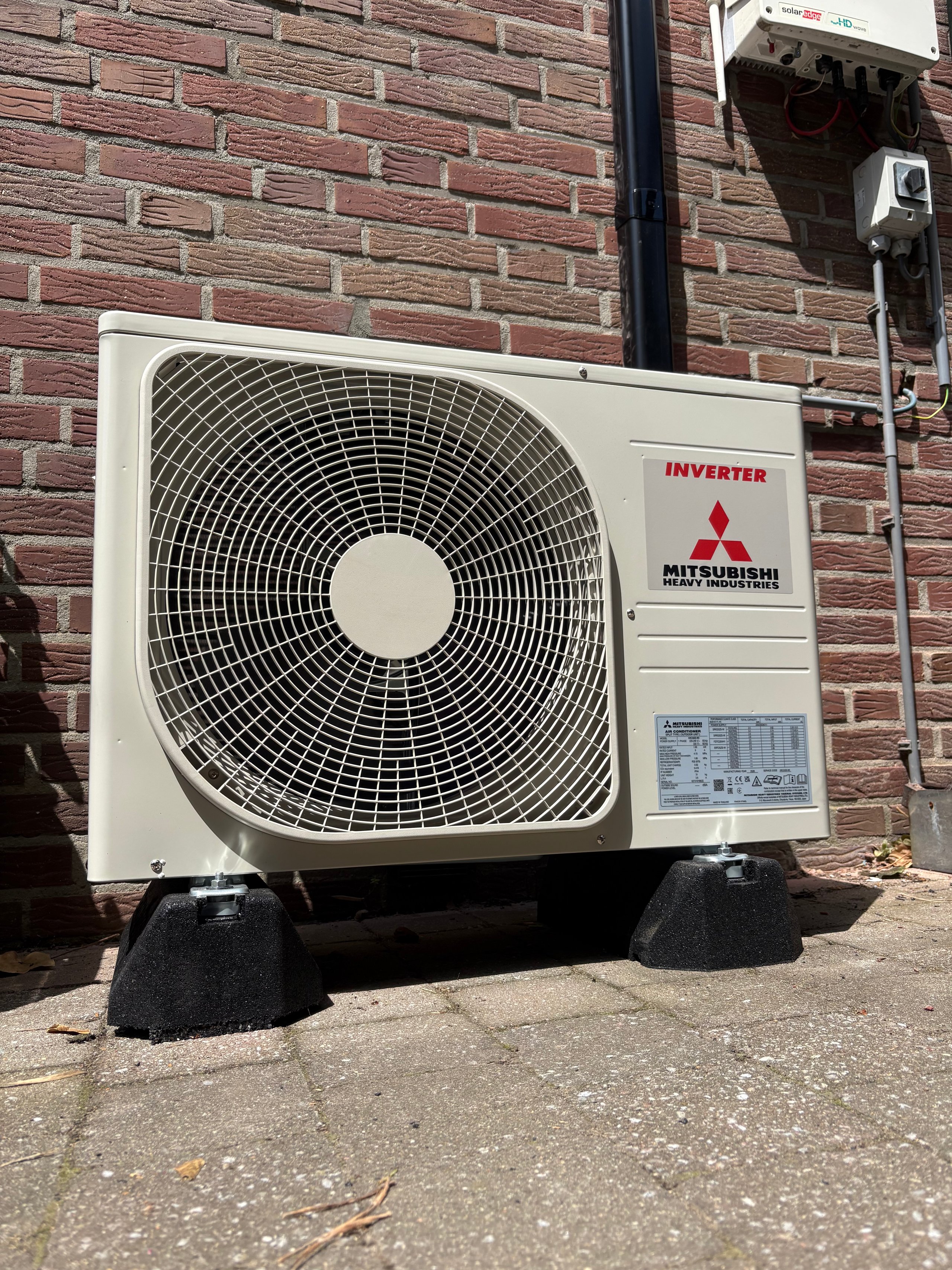 Mitsubishi inverter air conditioner outdoor unit mounted on brick wall with rubber isolation pads