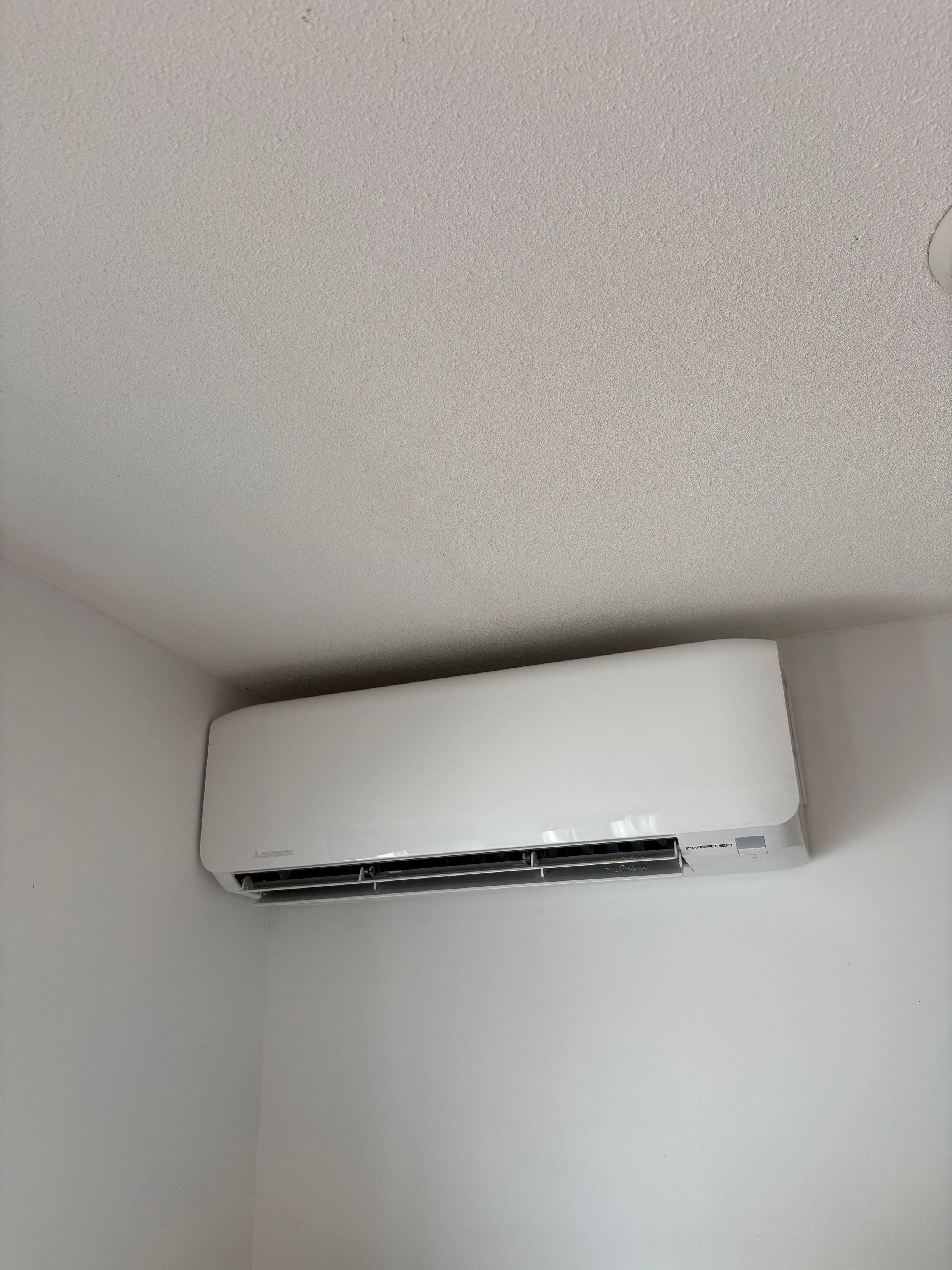 White ductless air conditioning unit mounted on a light gray wall