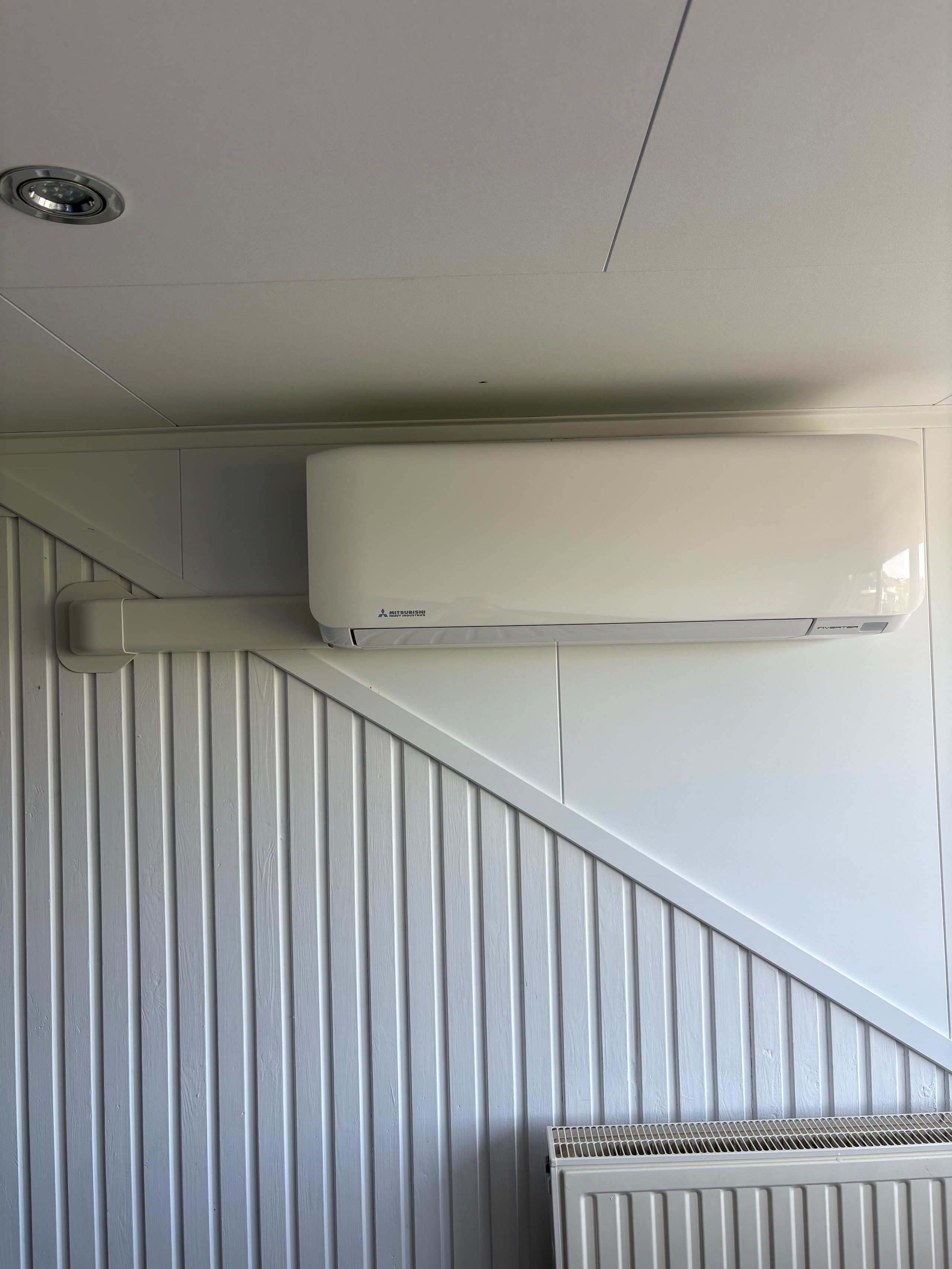 White split air conditioner unit mounted on wall above staircase