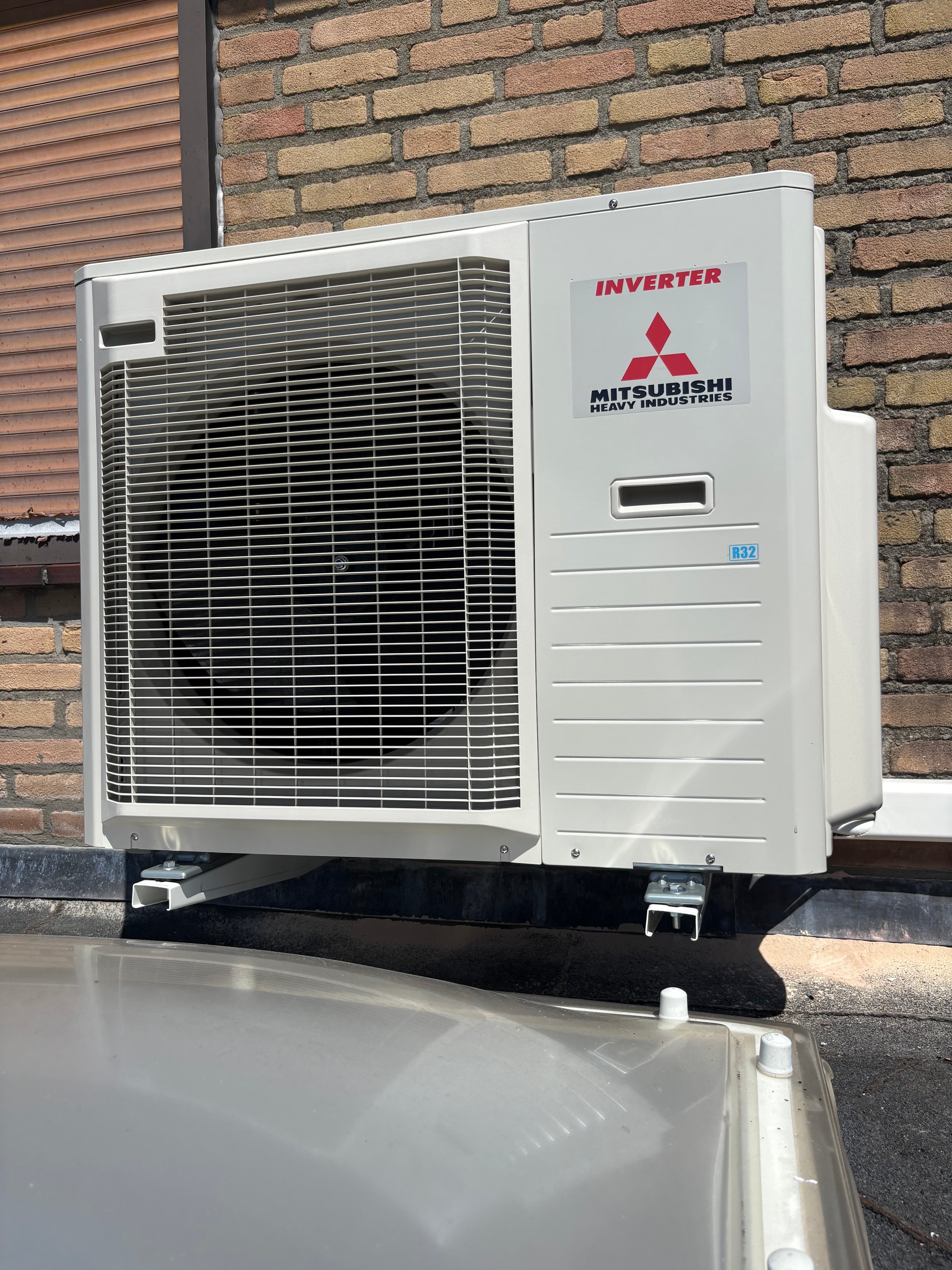 Mitsubishi inverter air conditioning unit mounted on exterior wall against brick building