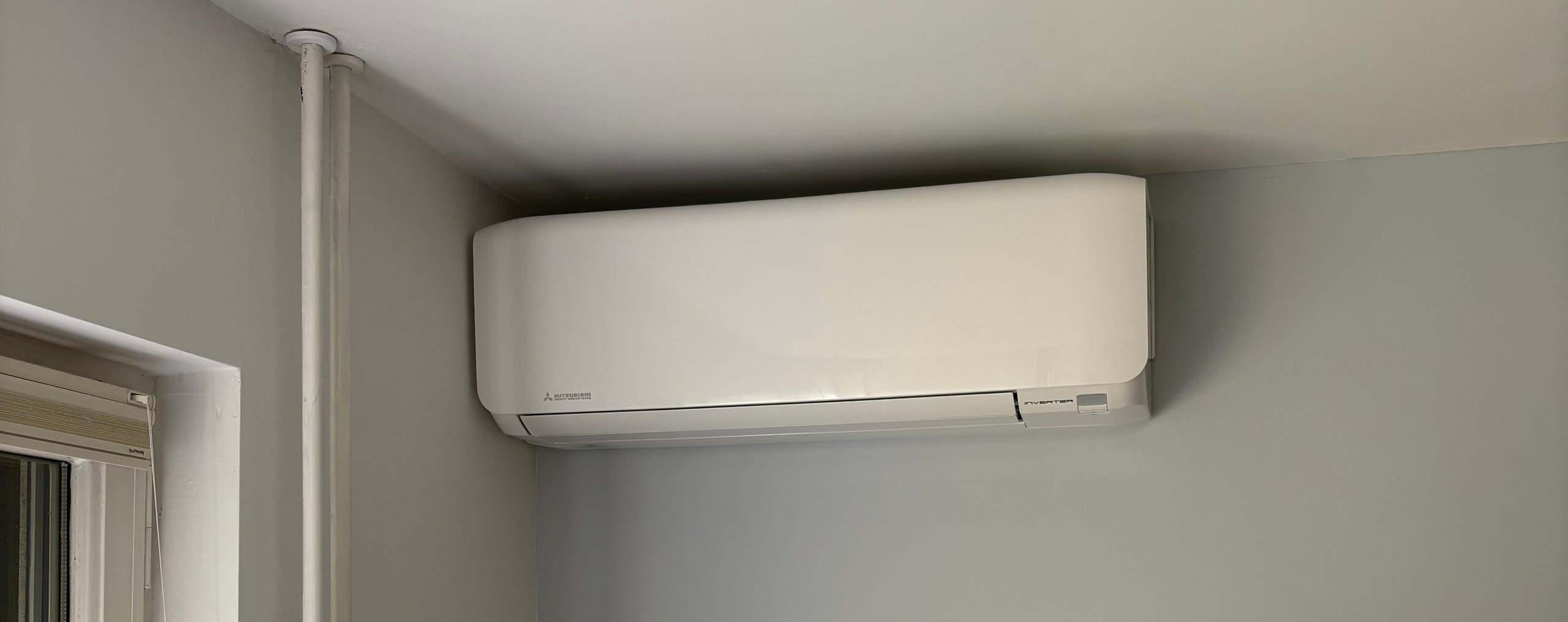 White ductless air conditioning unit mounted on gray wall near doorway