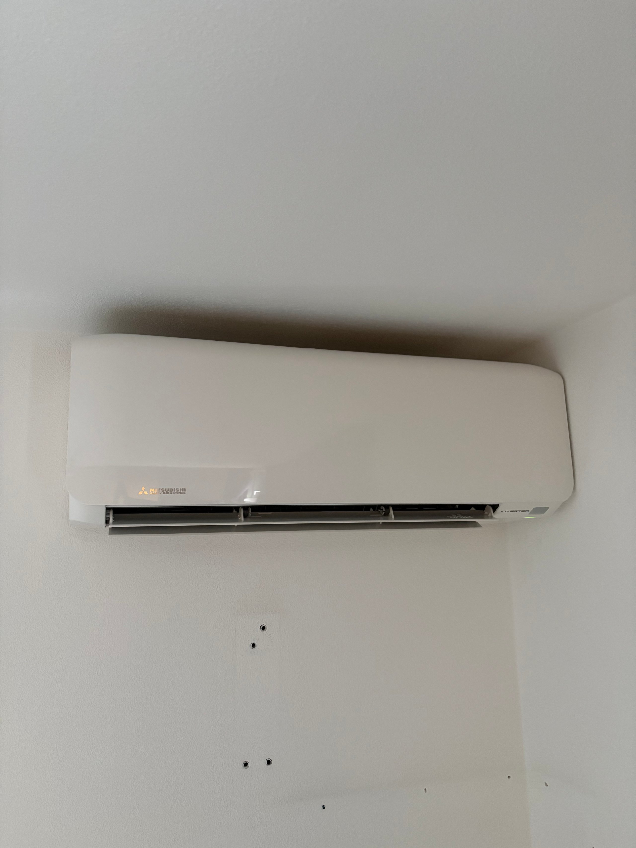 White split-type air conditioning unit mounted on a light gray wall