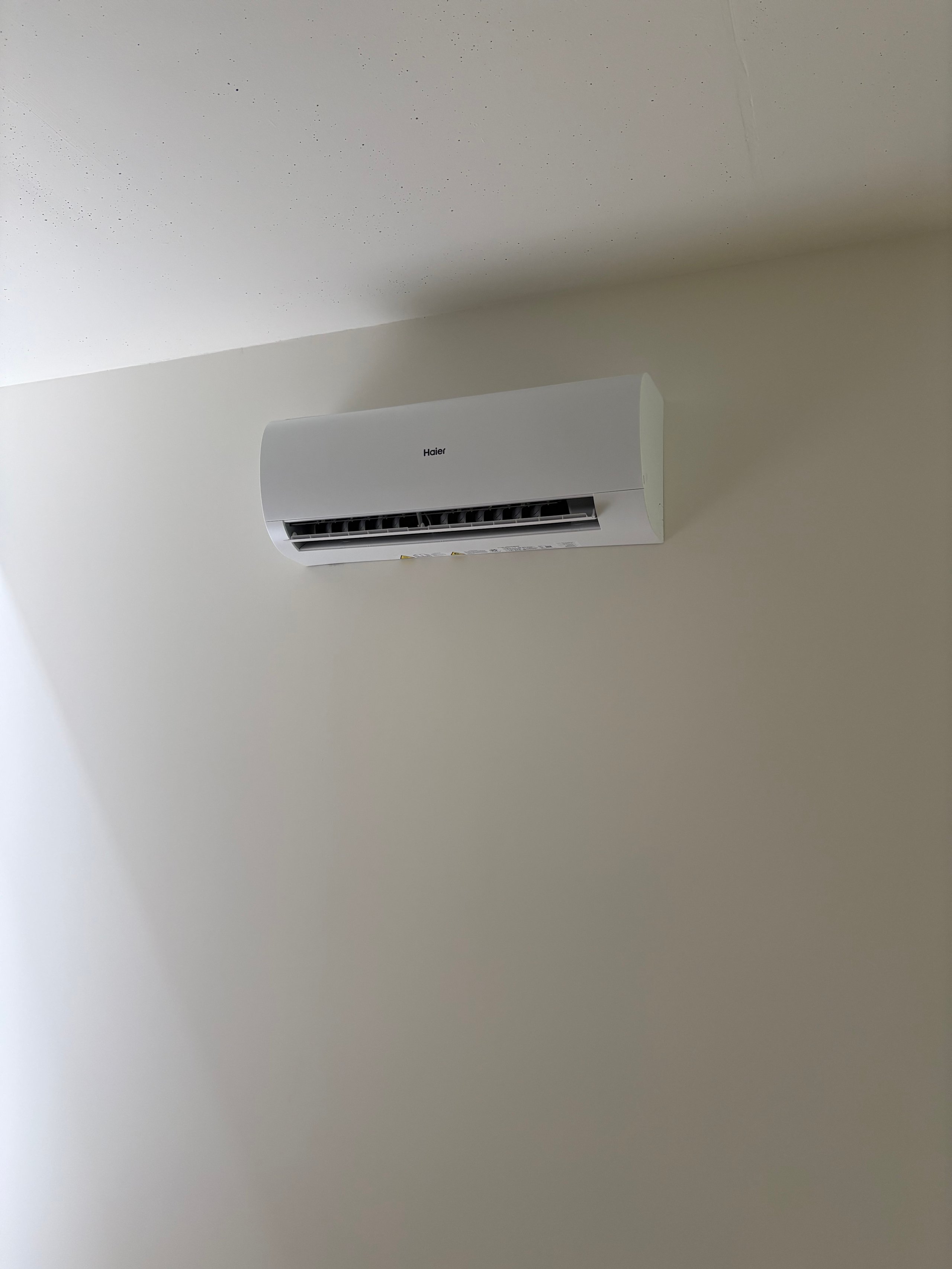 White split-type air conditioning unit mounted on a light gray wall